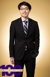 Professional headshot of a person wearing a suit, with The Husky 100 text