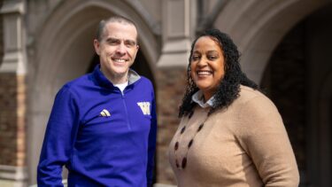 Two people smiling in front of a University of Washington building