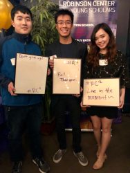 Three young scholars holding motivational signs at Robinson Center event